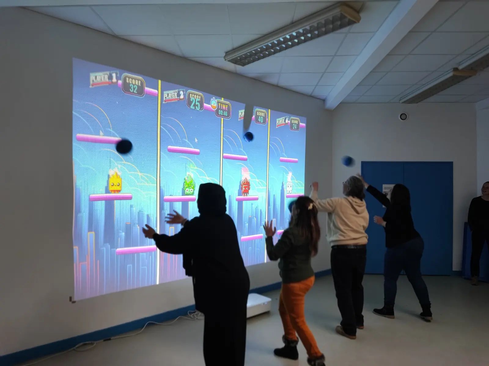 Groupe en pleine partie sur le mur interactif, jeu collectif au ballon